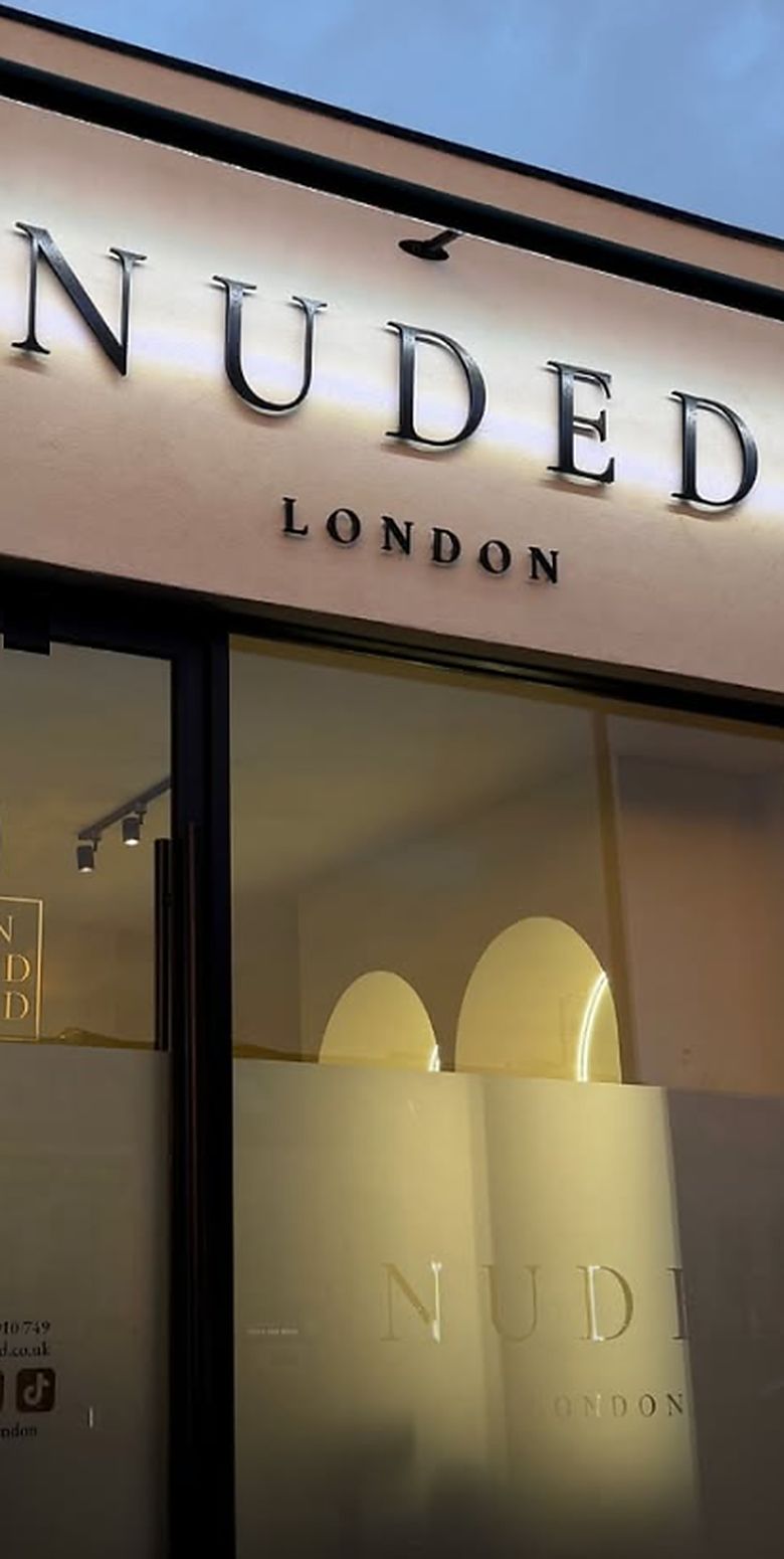The finished shopfront: a pale fascia carrying backlit NUDED LONDON lettering above full height glazing.